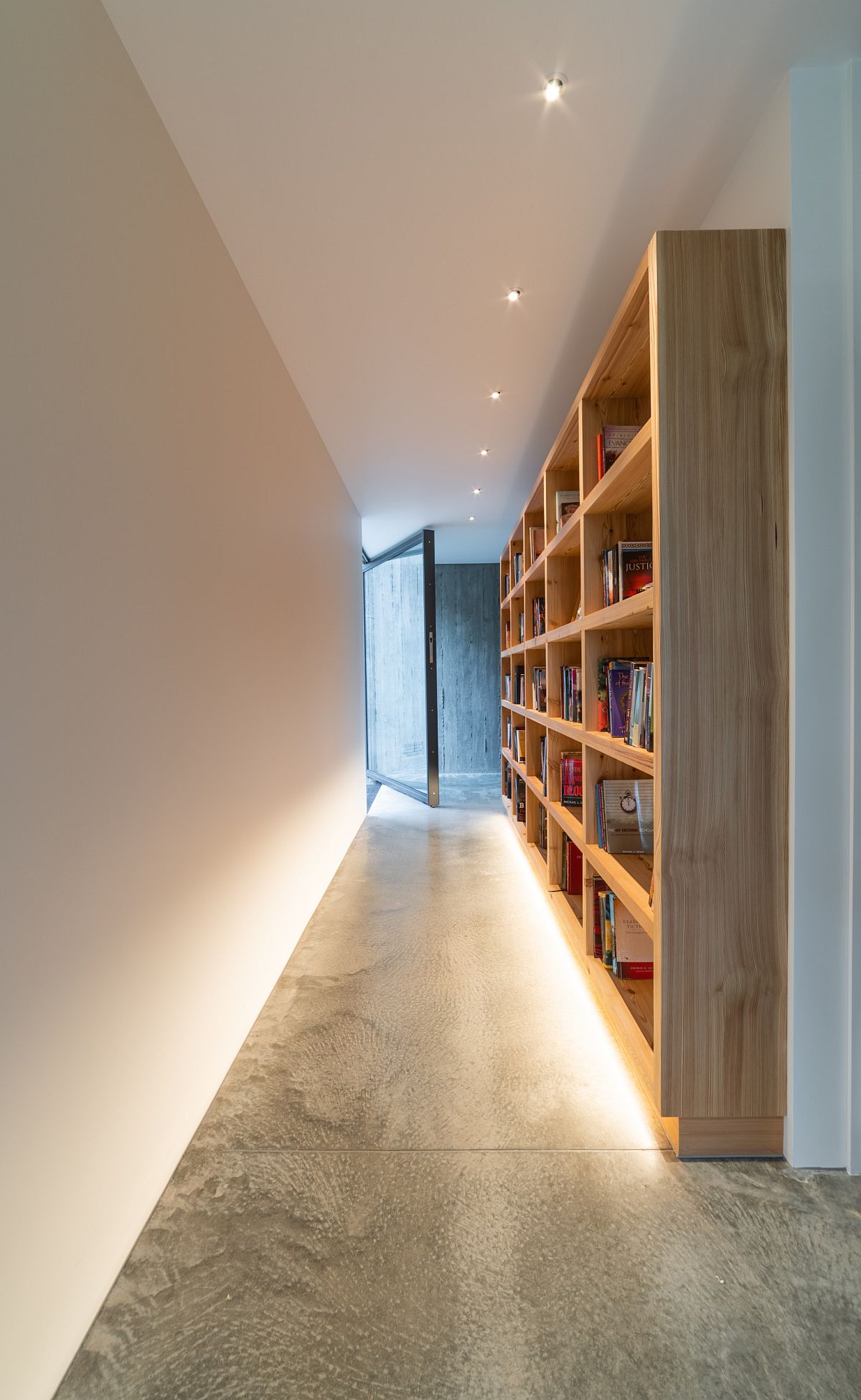 Giá sách gỗ tùy chỉnh ở hành lang thêm một cái gì đó khác biệt cho ngôi nhà hiện đại.