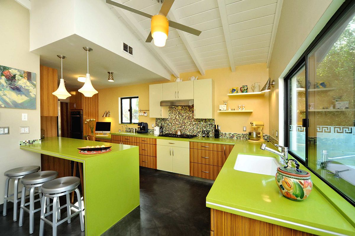 Nhà bếp hiện đại theo phong cách mid-century tuyệt đẹp với bức tường tạo điểm nhấn màu vàng và mặt bàn màu xanh lá cây bắt mắt.
