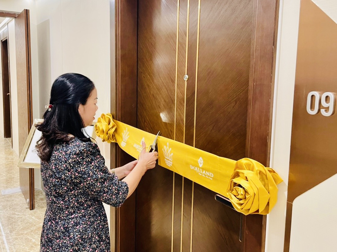 A person cutting a ribbon on a door  Description automatically generated