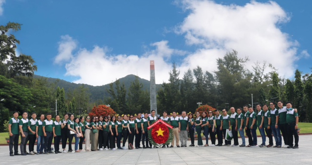 A group of people standing in front of a flag  Description automatically generated