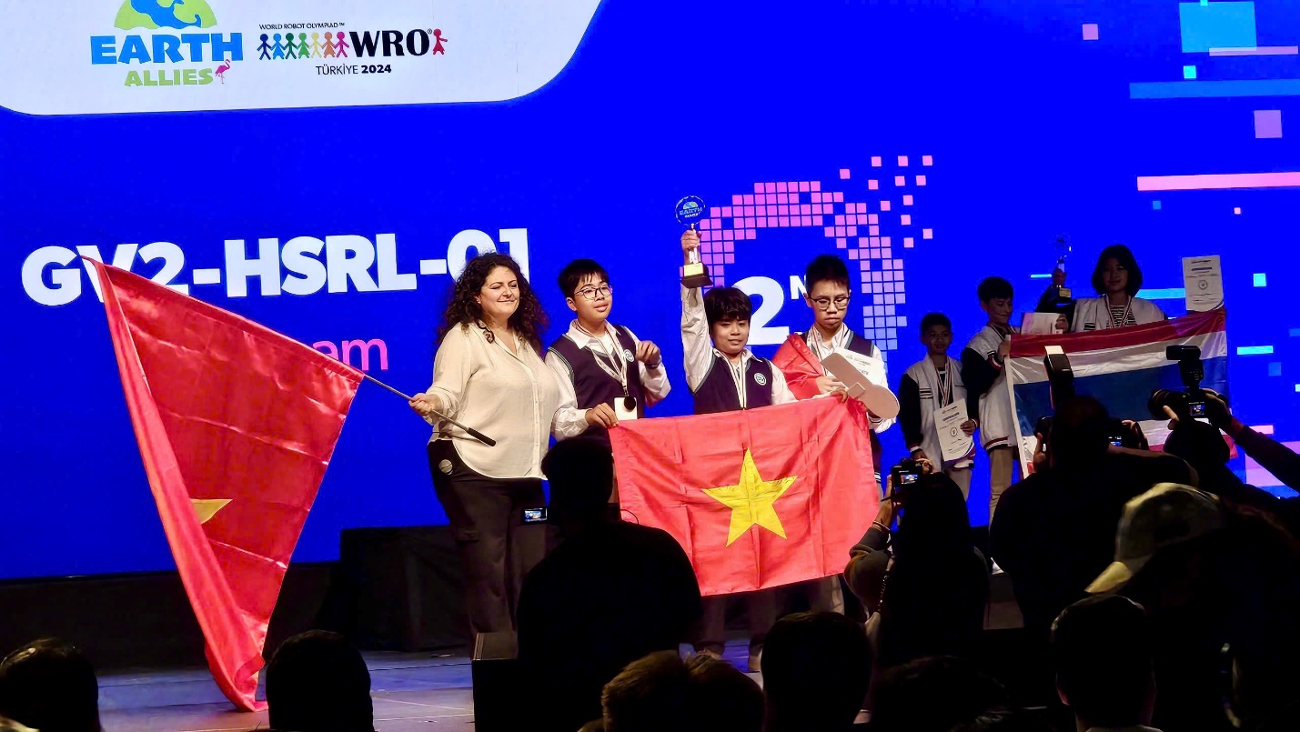 A group of people on a stage holding a flag  Description automatically generated