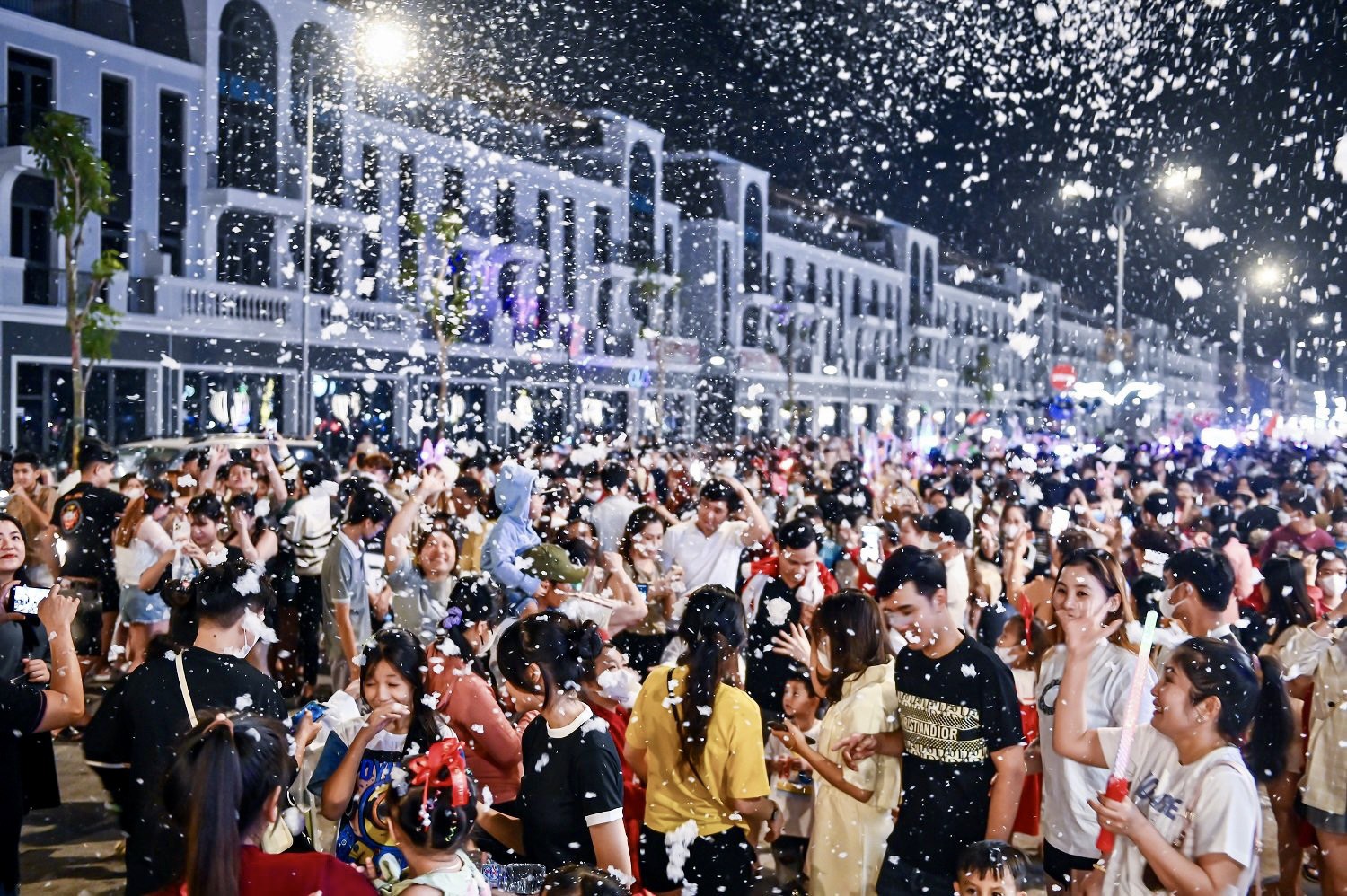 A crowd of people in a street with confetti  Description automatically generated