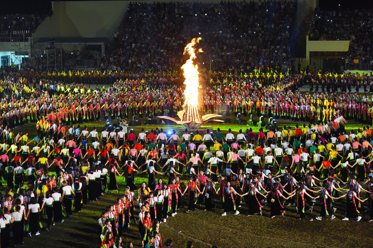 A large group of people in a circle with a fire in the background  Description automatically generated