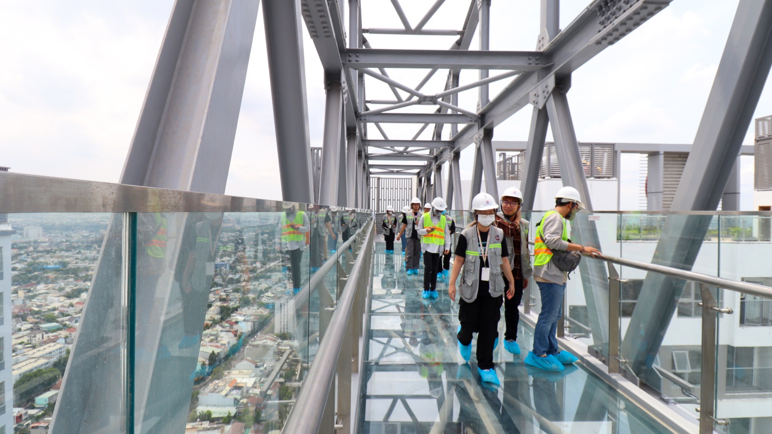 A group of people standing on a glass walkway  Description automatically generated