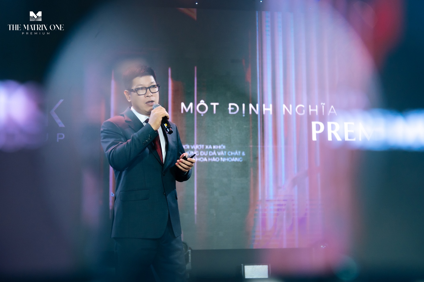 Trải nghiệm hành trình Timeluxe tại lễ giới thiệu The Matrix One Premium- Ảnh 5. A person in a suit holding a microphone AI-generated content may be incorrect.