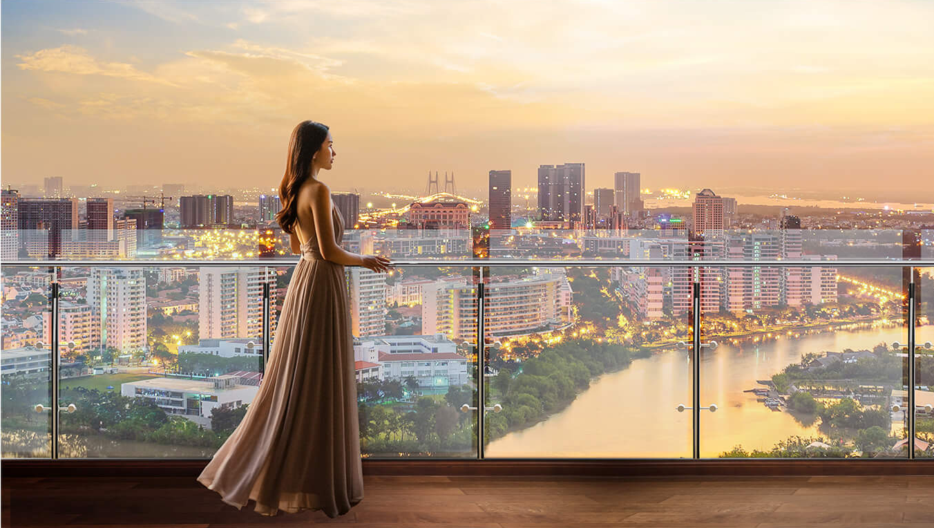Làn sóng đầu tư đổ về khu Nam Sài Gòn, bất động sản ven sông thăng hạng- Ảnh 2. A person in a dress standing on a balcony overlooking a city Description automatically generated