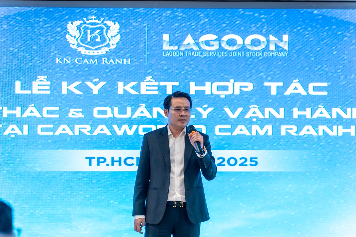 Tổ hợp ẩm thực - giải trí & nghỉ dưỡng 5* quốc tế sắp ra mắt tại CaraWorld- Ảnh 3. A person in a suit holding a microphone AI-generated content may be incorrect.