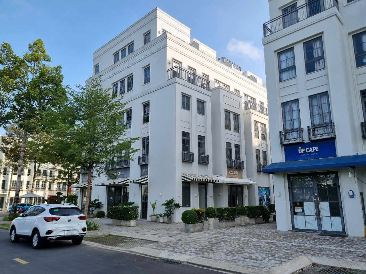 A white building with trees and a parking lot  AI-generated content may be incorrect.