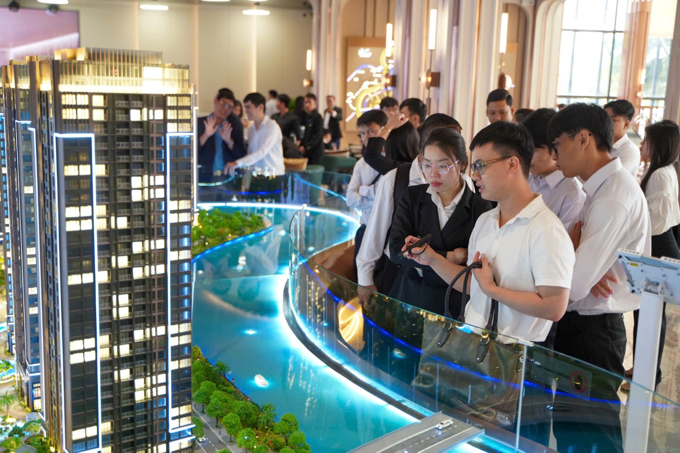 A group of people looking at a model of a building  Description automatically generated