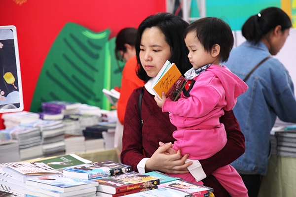 Bố mẹ có thể đưa con đi chọn sách để tăng sự hứng thú đối với bé. Ảnh: Nguyễn Bách.