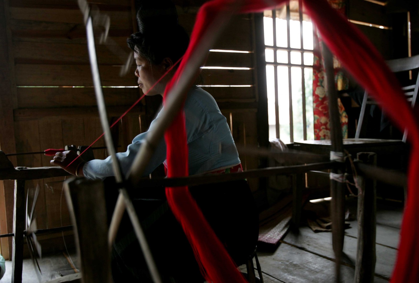 Chị Lò Thị Dóm bên khung cửi dệt thổ cẩm may túi, khăn piêu và các sản phẩm khác bán cho khách du lịch đến thăm bản văn hóa Him Lam II.