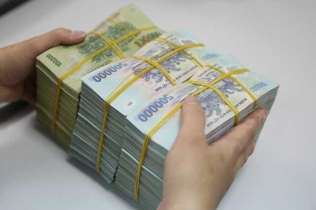 A person holds stacks of Vietnamese banknotes. (Photo: Thanh Hoa)