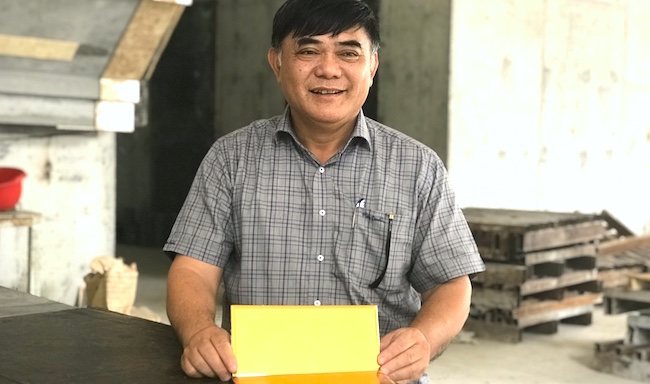 Nguyen Huu Duong with a gold-plated tile at the Hanoi Golden Lake construction site.