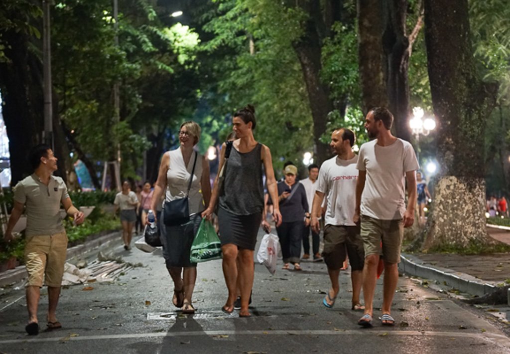 Local talks with foreigners at the pedestrian zone of Hoan Kiem Lake. (Photo: Thuong Nguyet/Hanoimoi)