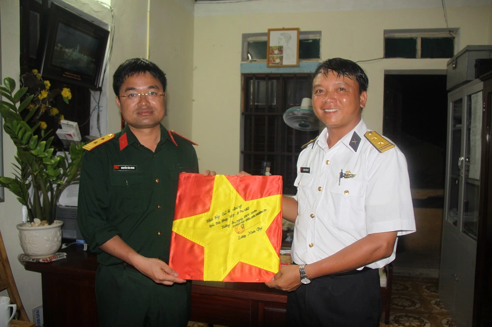 Nhà báo Nguyễn Văn Minh nhận lá Quốc kỳ từ đảo Trường Sa do Chính trị viên Lương Xuân Giáp trao tặng.