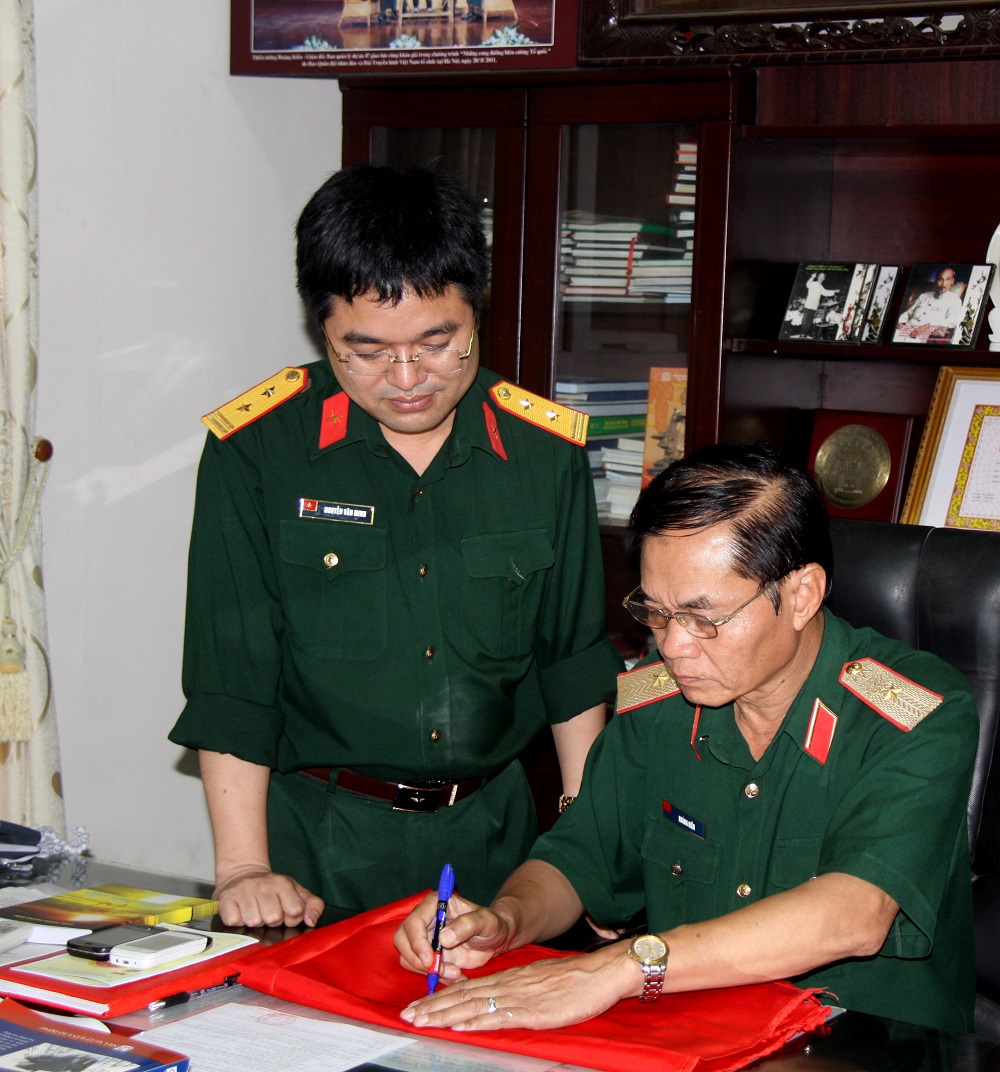 Nhà báo Nguyễn Văn Minh xin chữ ký Anh hùng LLVTND, Thiếu tướng Hoàng Kiền lên lá Quốc kỳ để mang ra quần đảo Trường Sa. 