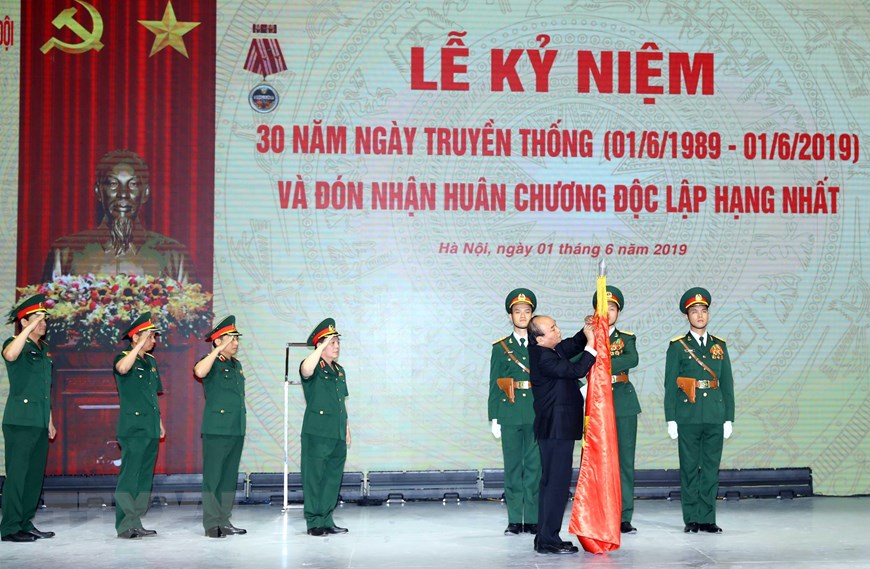 Thủ tướng Nguyễn Xuân Phúc, thừa ủy quyền Chủ tịch nước gắn Huân chương Độc lập hạng Nhất lên lá cờ truyền thống của Tập đoàn Công nghiệp - Viễn thông Quân đội. (Ảnh: Thống Nhất/TTXVN)