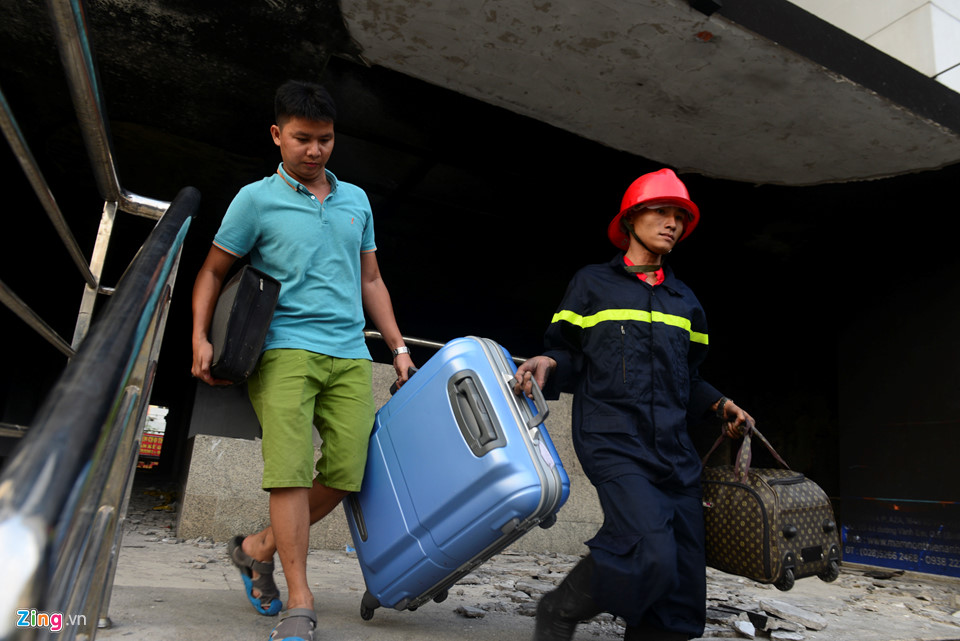 Anh Nguyễn Hữu Trực vận chuyển vali trong sự giúp sức của cảnh sát PCCC. Anh cùng gia đình qua nhà người thân đối diện đó xin ở nhờ.