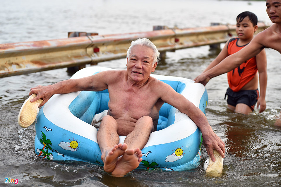 Ông Hà Danh Bình (71 tuổi) cho biết có thể bơi xa nhưng hôm nay được dịp vùng vẫy nhiều giờ nên mệt, nhờ con cháu mang phao ra nằm lênh đênh trên nước.