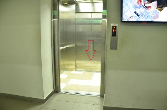 Thang máy chuyển hàng mà ông Trí gặp nạn (trong ảnh là cửa thang máy mở để khách đi vào và mũi tên đỏ phía sau là cửa ra nếu thang di chuyển lên tầng G hoặc tầng 1)