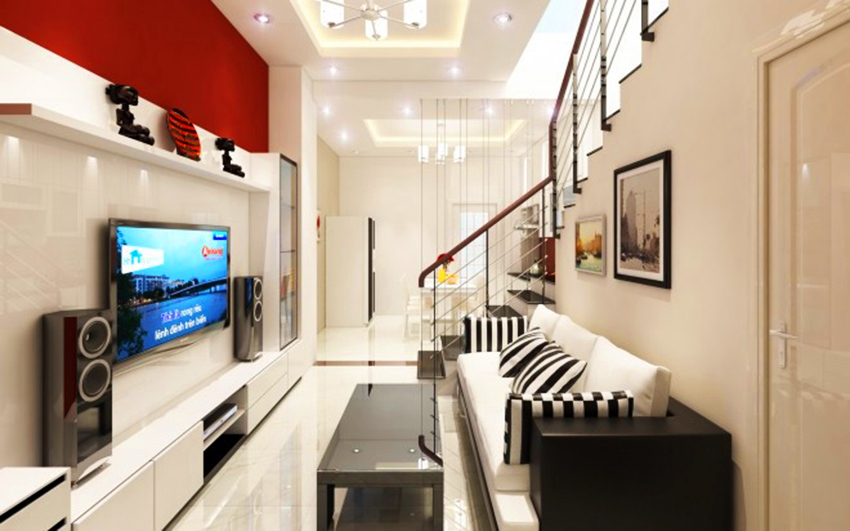 Phòng khách gia đình với tông màu trắng chủ đạo, mảng nhấn ấn tượng màu đỏ, phong cách hiện đại. Kệ TV và trang trí kết hợp giải trí là mảng nhấn ấn tượng cho không gian phòng khách. Ảnh: Viphouse