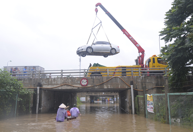 Một chiếc ô tô 4 chỗ không thể di chuyển qua đoạn ngập, chủ chiếc xe phải thuê xe cẩu từ dưới chỗ ngập lên mang đi sửa chữa/ Ảnh: Dân Việt