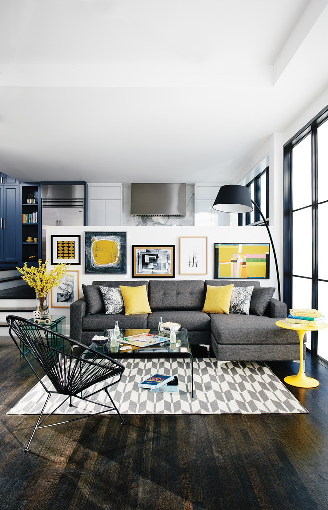 Phòng ngủ hiện đại với ghế sofa màu xám, gối, bàn, tranh treo tường màu vàng kết hợp với sàn màu tối càng làm nổi bật lên gam màu vàng, tăng thêm sự hiện đại trẻ trung cho ngôi nhà.