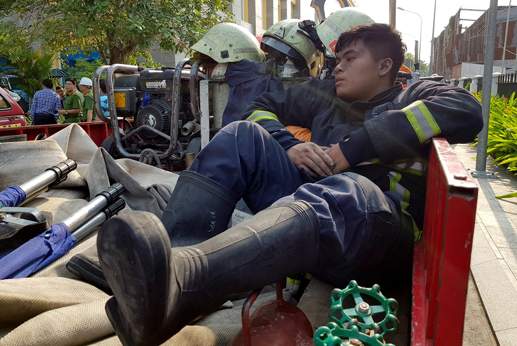 Lính cứu hỏa mệt nhoài, nằm trên xe chữa cháy nghỉ ngơi sau một đêm chữa cháy. Ảnh: Lê Trai.