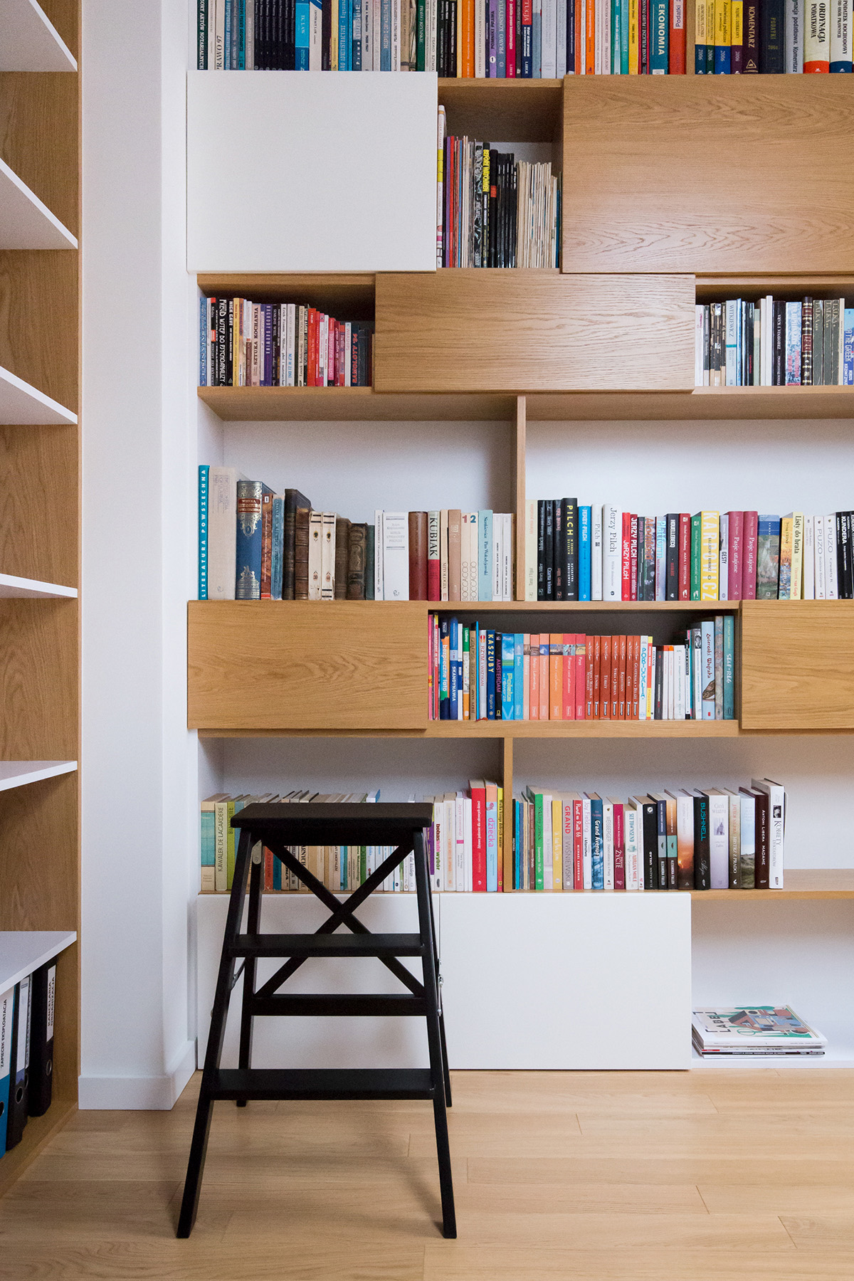 Tủ sách cũng được pha trộn giữa màu gỗ và màu trắng với một thang nhỏ màu đen.