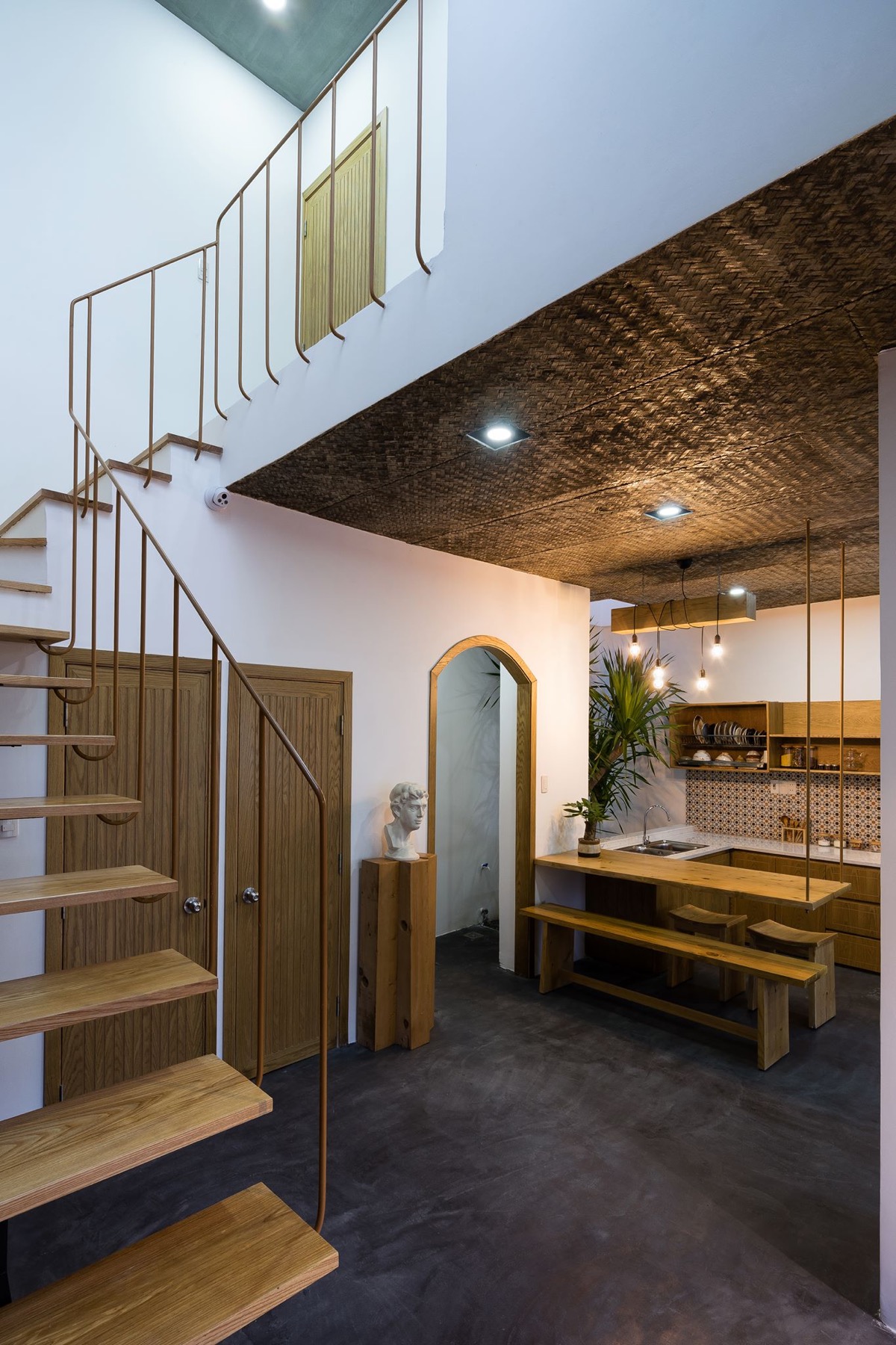 Khu bếp ăn kết nối trực tiếp với khoảng sân trong nhà, sàn bê tông chạy liền mạch giữa hai không gian và tông màu gỗ mật ong tạo cảm giác rộng rãi.