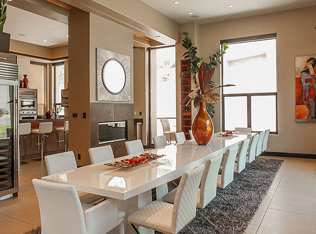 Phòng ăn sử dụng bộ bàn ghế màu trắng, dài hết không gian bên cạnh một lò sưởi ấm cúng.