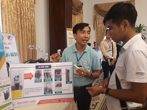 Thầy giáo trẻ Hồ Văn Tuấn (trái) giới thiệu sản phẩm cho một khách tham quan về hệ thống xử lý nước của mình sáng chế. Ảnh: Hà Thế An.