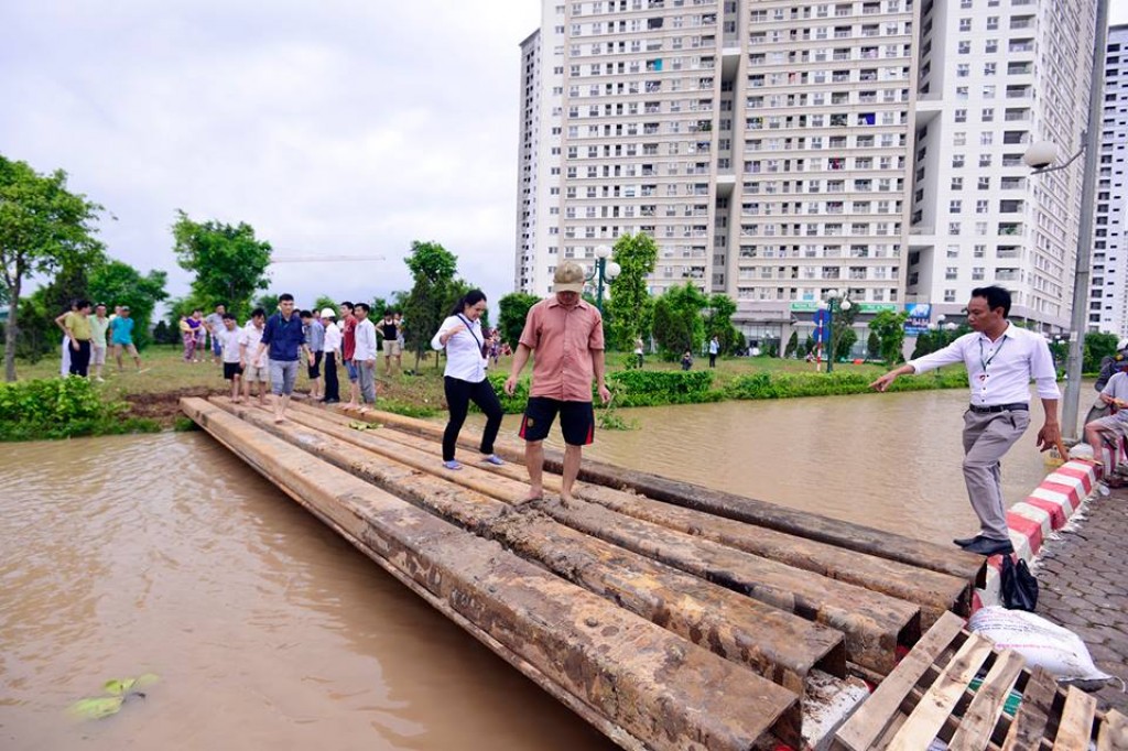 Người dân khu đô thị Dương Nội vượt qua nơi ngập bằng cây cầu tạm bợ.
