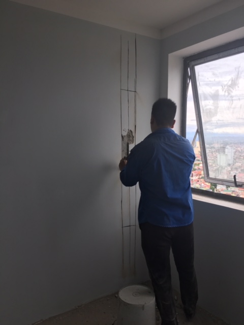 Thợ của chung cư Bảo Sơn đang sửa chữa tường xây căn hộ bị nứt.