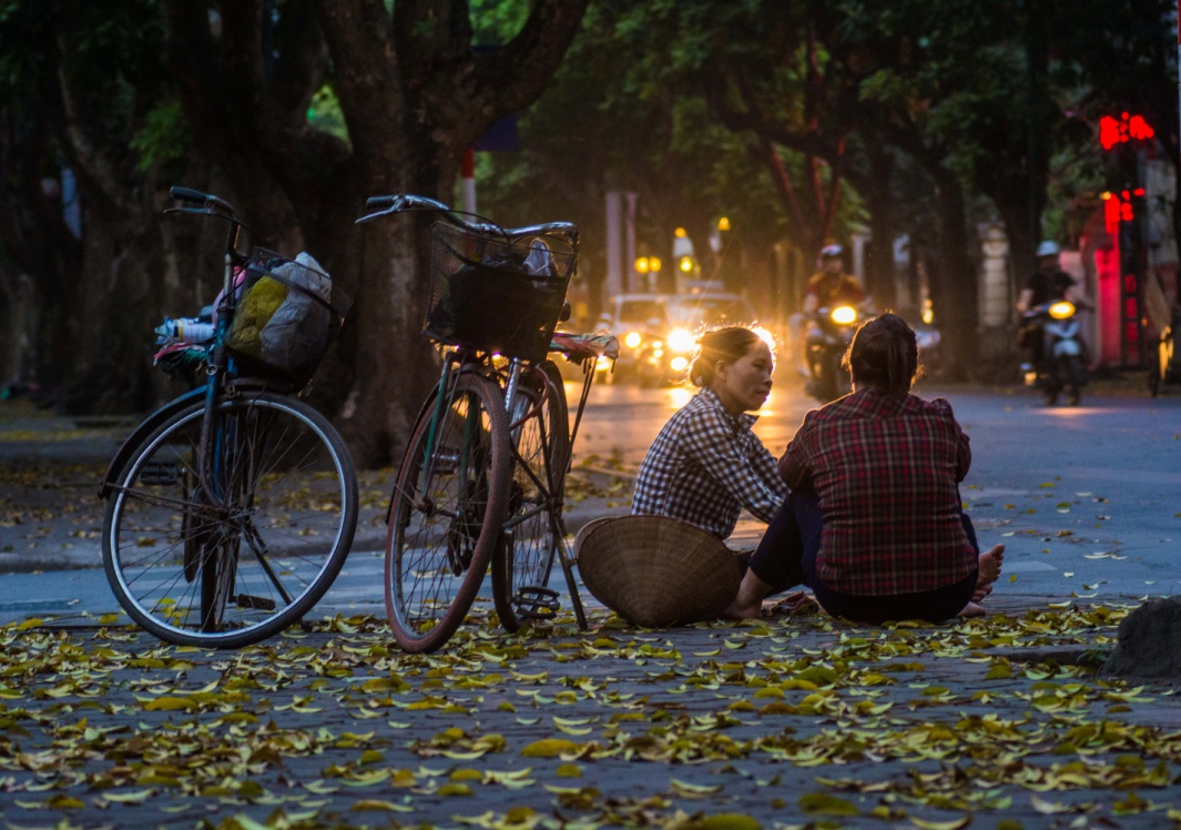 Hai người phụ nữ bên chiếc xe đạp cũ kĩ – là phương tiện đi lại, mưu sinh giữa lòng thành phố phồn hoa.