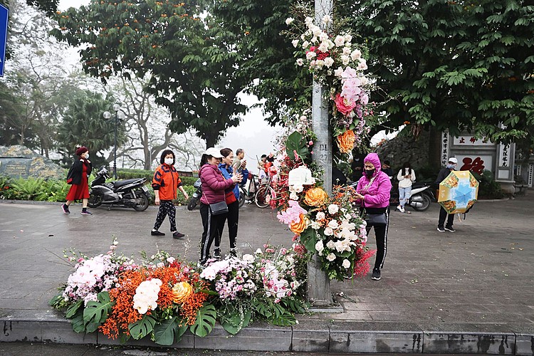 Sáng 8/3, người dân quanh khu vực hồ Hoàn Kiếm bất ngờ khi những cột đèn bỗng biến thành cột hoa tươi rực rỡ sắc màu. Những khóm hoa được trang trí tỉ mỉ, uốn lượn quanh thân cột, tạo thành điểm check-in độc đáo trong ngày Quốc tế Phụ nữ. Ảnh: Ngọc Thành.