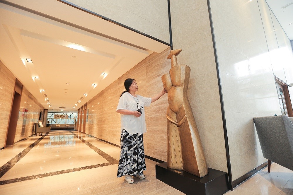 Họa sỹ Nguyễn Thị Kim Thái đứng sát bên các bức tượng
