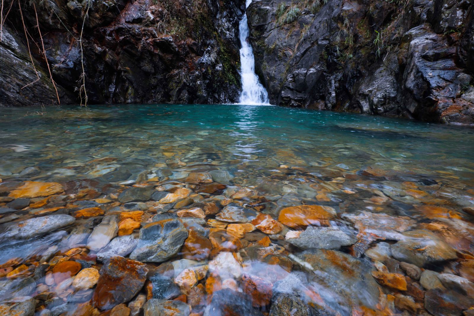 Dòng nước luồn qua những khe đá đổ xuống hủng sâu tạo nên một hồ nước nhỏ trong vắt, với xanh màu ngọc bích của nước và đá suối long lanh…