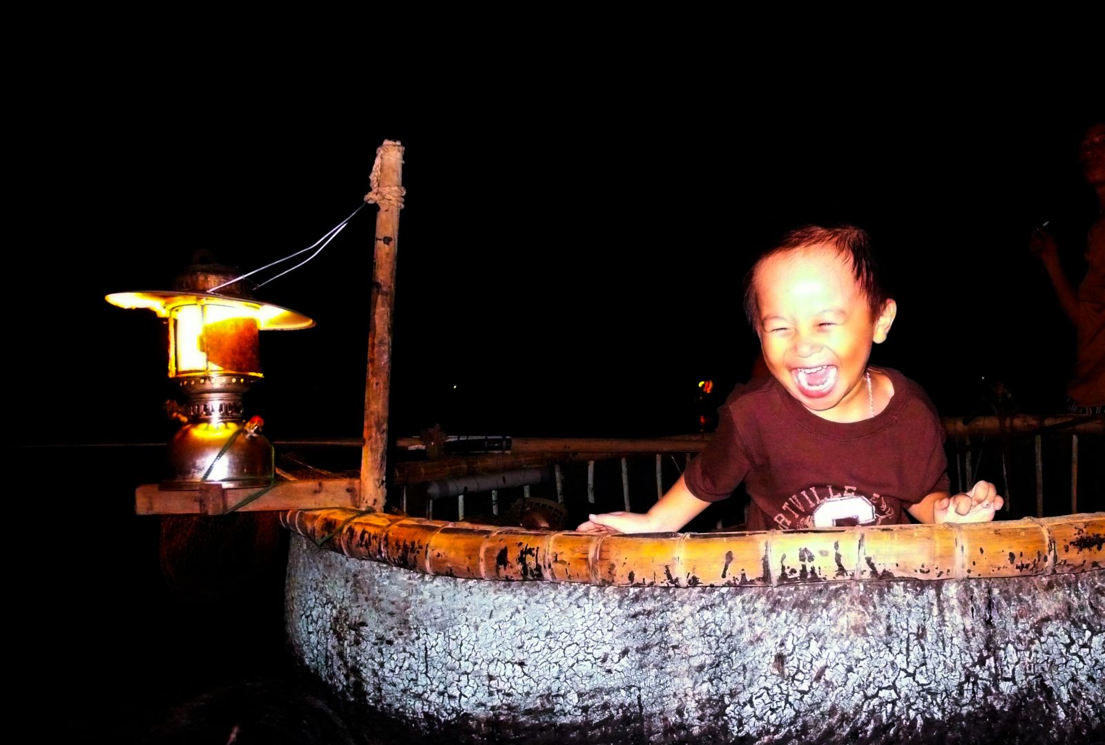 Các em bé theo gia đình đi nghỉ thích thú khi được đứng trên những chiếc thuyền thúng sáng đèn trên các bãi tắm ở biển Cửa Lò.