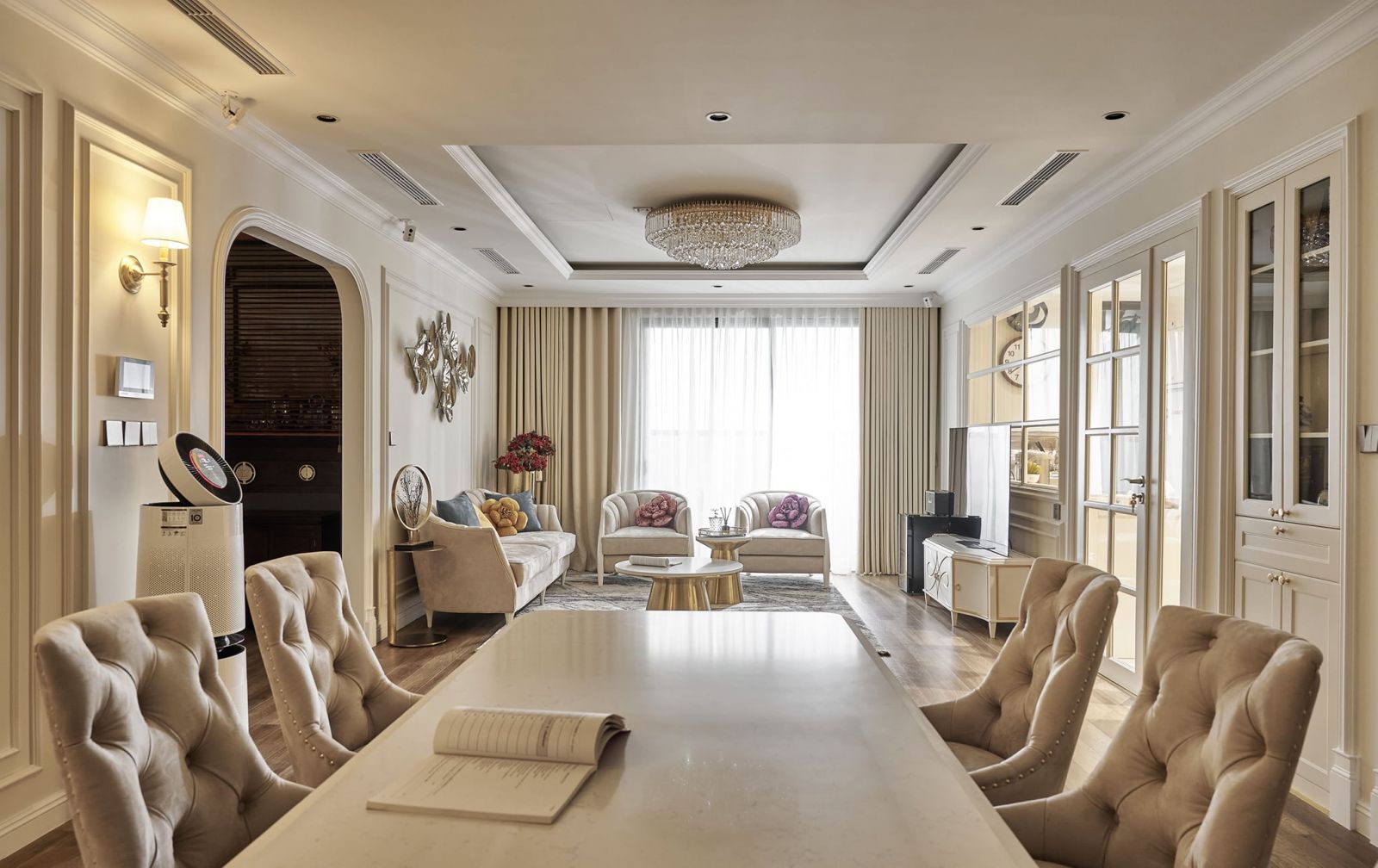 Phòng khách được thiết kế theo phong cách tân cổ điển với tông màu nude, điểm nhấn là chiếc đèn chùm cùng bộ ghế sofa lớn.