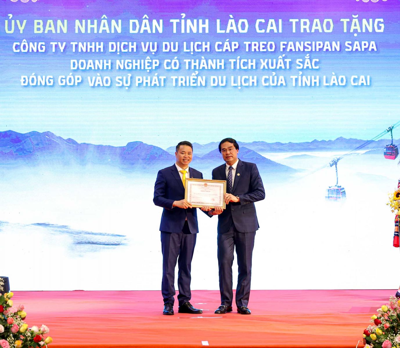 Ông Trịnh Xuân Trường - Chủ tịch UBND tỉnh Lào Cai (phải) trao bằng khen cho ông Nguyễn Xuân Chiến, giám đốc KDL Sun World Fansipan Legend, ghi nhận những đóng góp của doanh nghiệp với sự phát triển của du lịch tỉnh Lào Cai